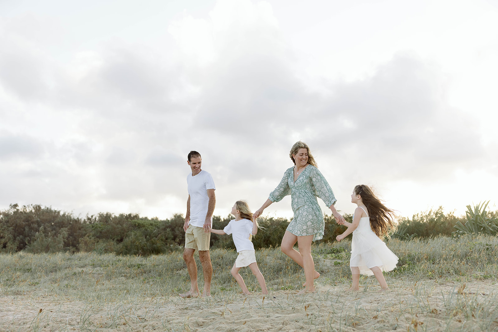 family holding hands and walking along the beach