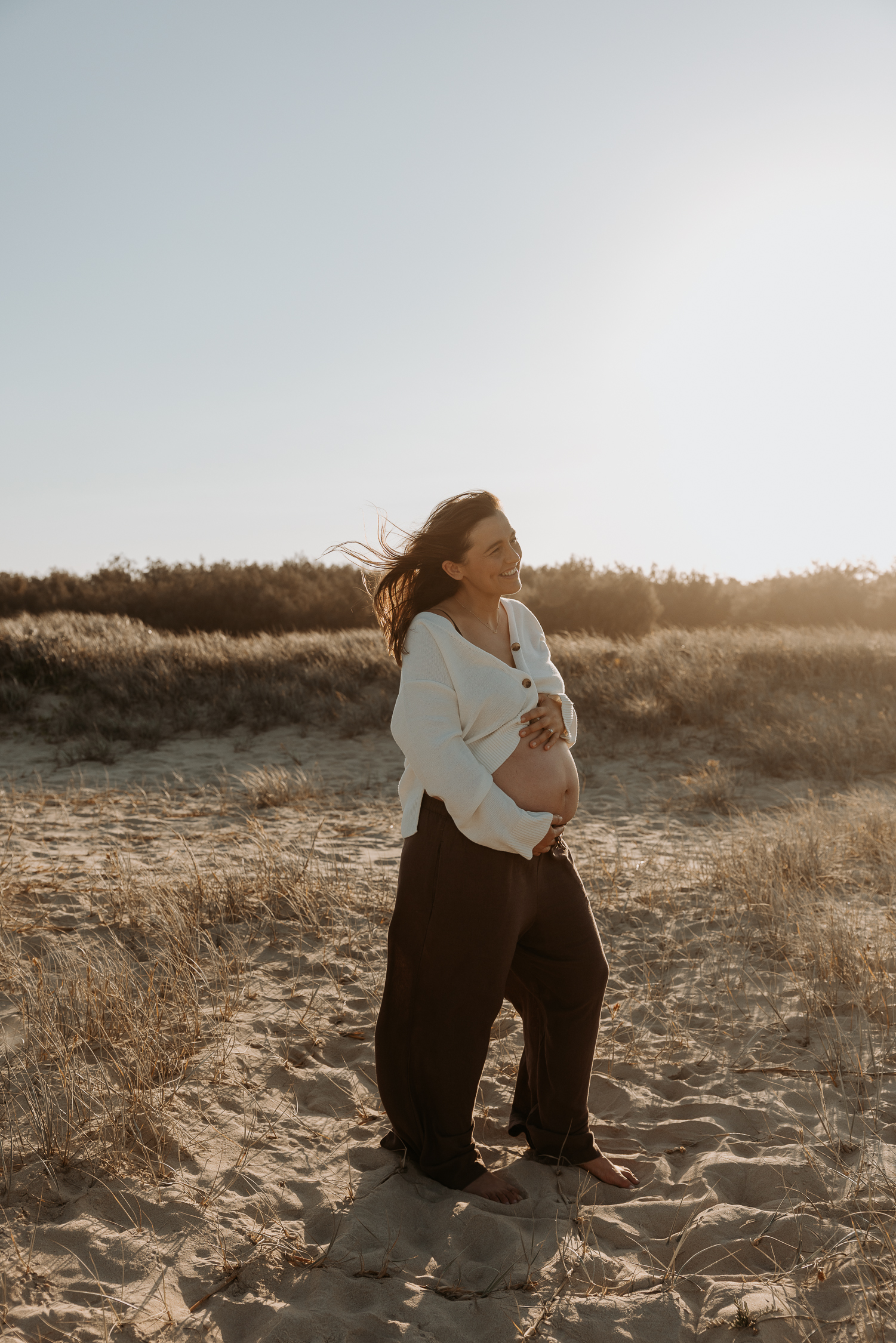 pregnant lady at the beach holding her tummy