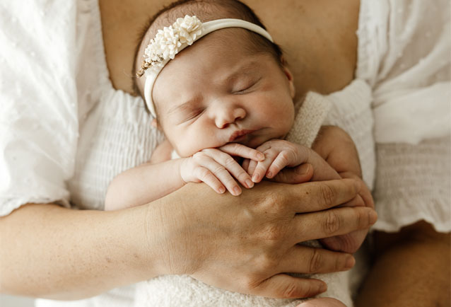 newborn baby sleeping against mothers chest